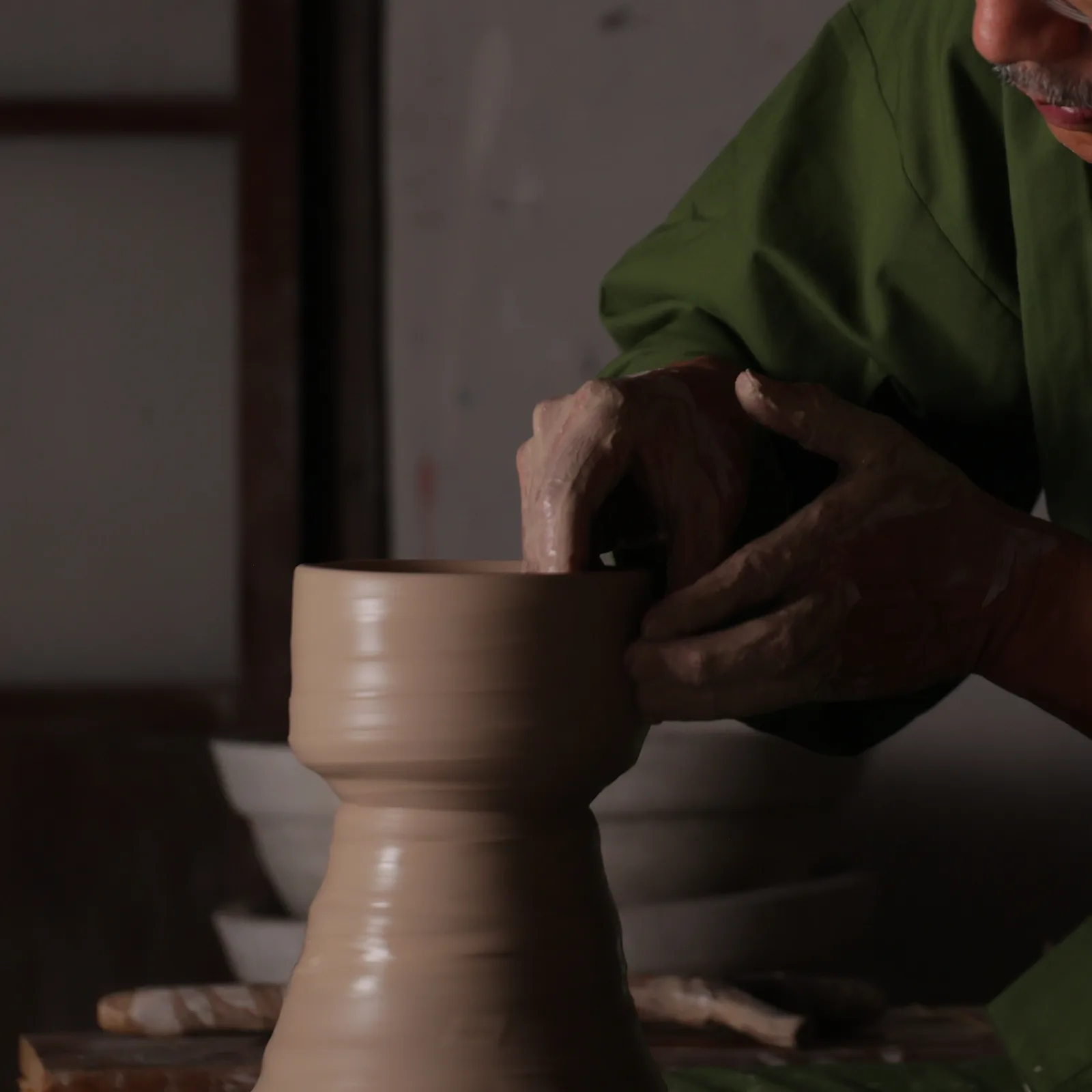 ろくろの上の器に手を添える、作家の手元