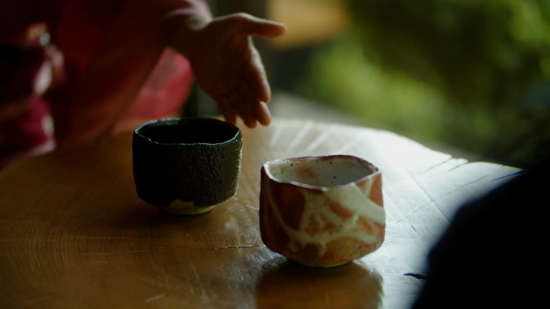 木の卓に並べた瀬戸黒と志野の茶盌に、手を伸ばして選ぶ