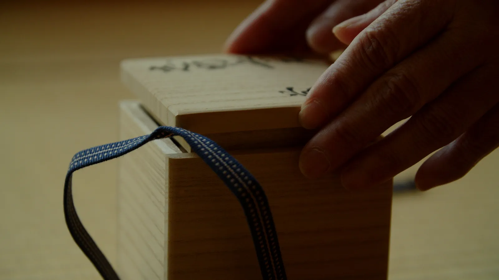 箱書きのある桐箱の蓋を閉める作家の手