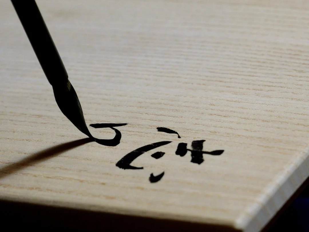 桐箱の蓋に、筆で「志野」と箱書きを書く筆先
