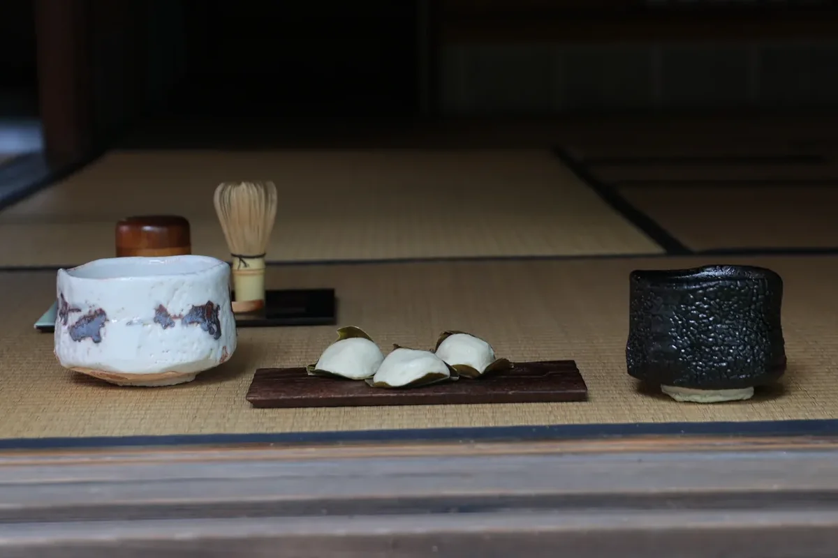 縁の畳に並べた、白い志野と瀬戸黒の茶盌、茶筅と菓子