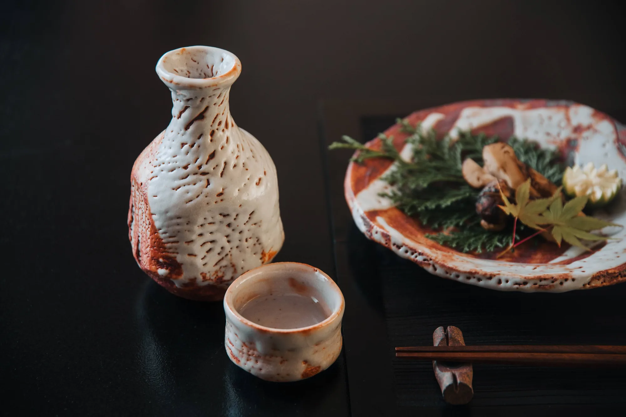 灯りの中の、志野の徳利とぐい呑み、料理を盛った志野の皿